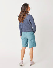 Back view of Woman wearing light blue jean shorts and the navy blue stripe Bodie funnel Neck, Carve Designs
